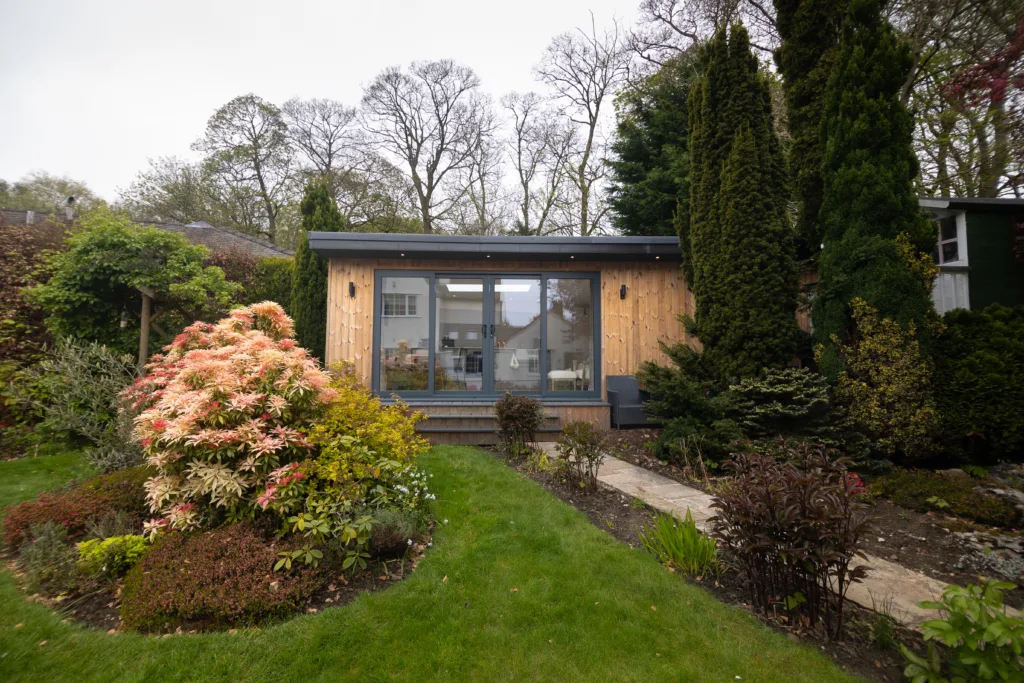 Outdoor room with grey bi-fold doors and steps to decking, garden in foreground